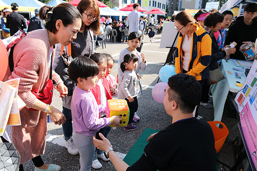 체험부스 앞에서 아이들과 직원이 얘기를 나누고 있는 사진