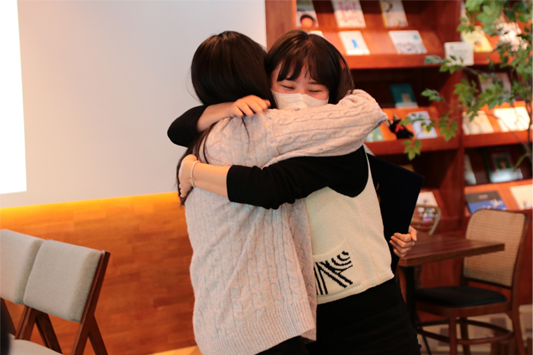 (오른쪽 아래 사진)여성직원 2명이 서로 포옹하며 응원하는 모습